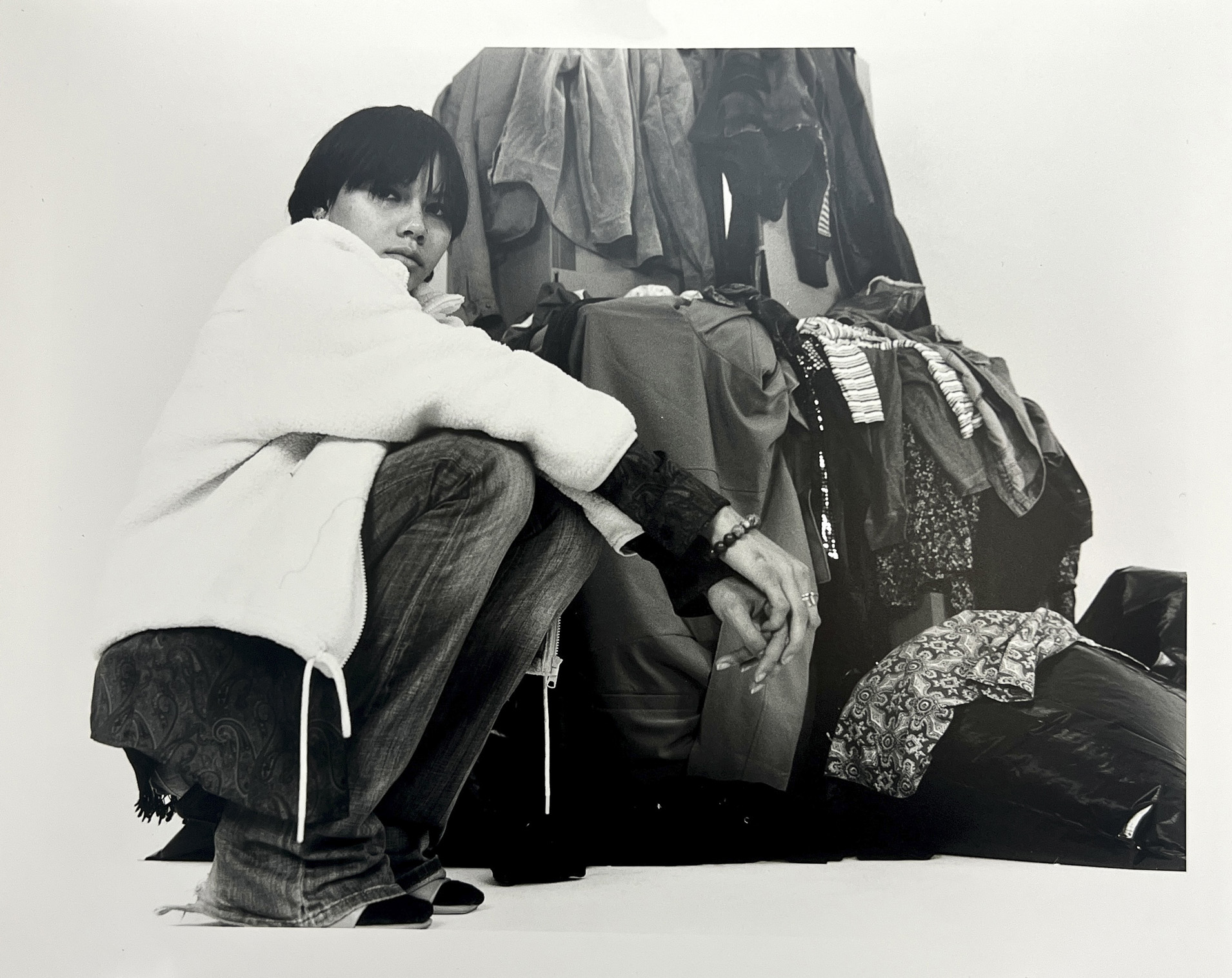 A person kneels near many pieces of clothes
